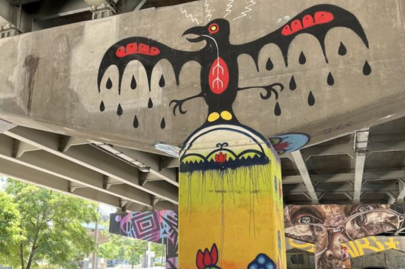 Thunderbird raining on the Land with flowers painted on a column in Underpass Park, Toronto.